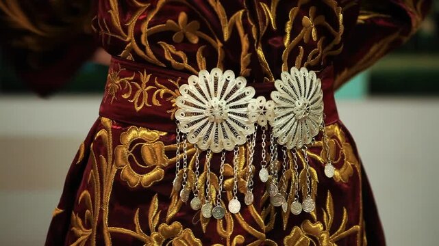 Woman adjusting ornate silver filigree belt on traditional embroidered Ottoman velvet caftan dress, close up