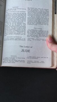 Opening to the book of Jude, of the New Testament in the Holy Bible. New Revised Standard Version. Vertical video.
