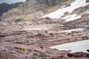 A breathtaking high-altitude mountain landscape featuring striking layered red rock formations contrasting with patches of melting snow. This serene nature scene is perfect for environmental themes © Viks
