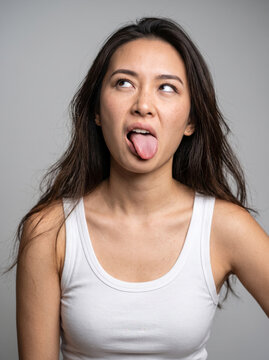 Playful Young Woman Looking Up While Sticking Out Her Tongue
