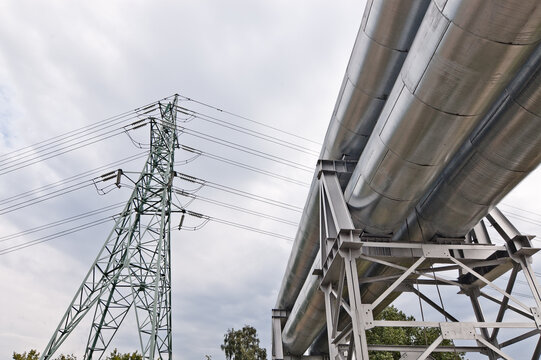 a pipeline and a power transmission tower against a gray sky