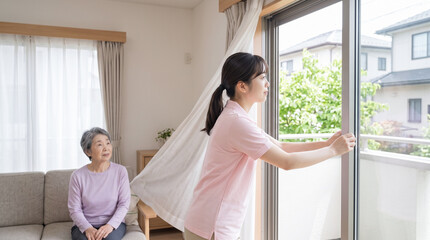 Fototapeta premium 高齢女性が見守る中で窓を開けて換気をする女性訪問介護スタッフ
