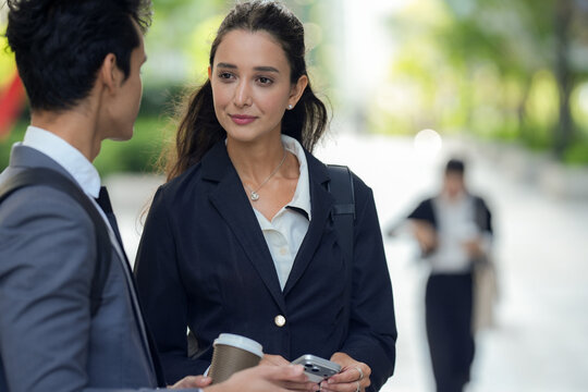 A confident multicultural business trio exchanging ideas in a two person chat on a broad avenue in a modern downtown, an honest snapshot of career life outside the office walls