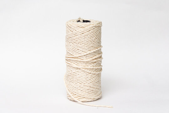 Cream cotton twine spool with loose end isolated on a white background