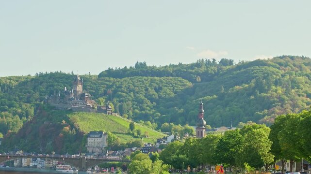 Breathtaking cinematic landscape video focusing on the majestic Reichsburg Cochem medieval castle nestled among lush green vineyards and hills in the scenic Moselle valley, Germany