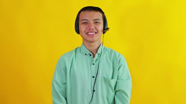 Friendly Asian customer service agent wearing headset smiling against bright yellow background