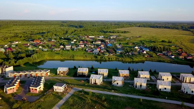 Aerial view of a modern residential neighborhood with cottage houses near a pond at sunset