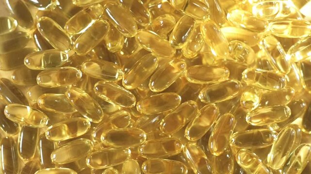 Close-up of golden omega-3 capsules stacked together, highlighting their shiny surfaces and smooth shapes in a well-lit setting