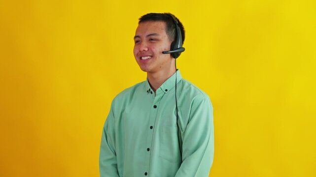 Side profile Cheerful Asian call center operator talking and laughing isolated on bright yellow background