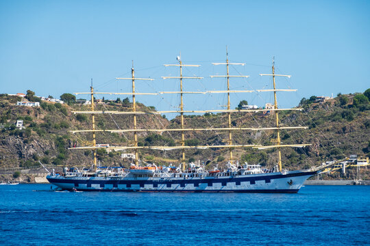 Lipari, ME - IT - Sep 06, 2026 : Four-masted Star Clippers sailing ship rests on blue harbor water with a rugged inhabited hillside rising behind it under a clear sky.