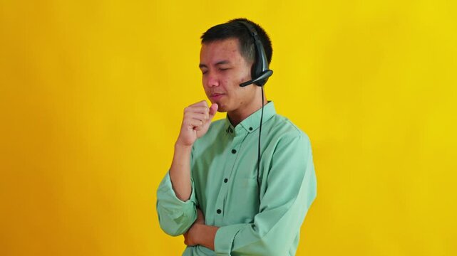 Asian customer service operator wearing headset feeling unwell and coughing on yellow backdrop