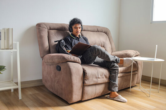 Male Freelancer Relaxing On Single Couch Holding Document Exploring Remote Educatio