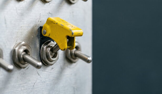 Toggle switch with yellow safety cover in "OPEN" position on industrial control panel, automation and power activation concept.