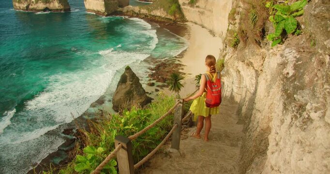 Woman looking at ocean and Diamond Beach from cliff stairs in Nusa Penida Bali