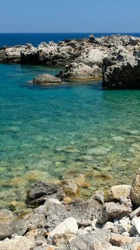Vertical video of rocky shore of Crete Island with turquoise clear Mediterranean sea water. Greece