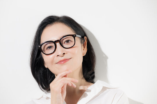 [白背景]眼鏡をかけた50代女性のポートレート、知的で落ち着いた印象のミドル世代とアイウェアのイメージ クローズアップ 　カメラ目線