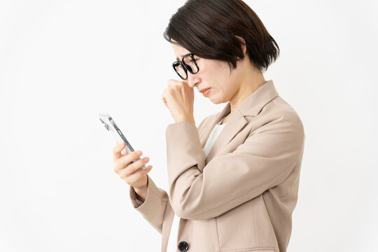 スマトフォンを使う眼鏡をかけたスーツ姿の女性