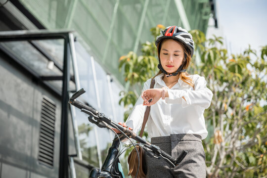 businesswoman standing with bicycle checking time on city street