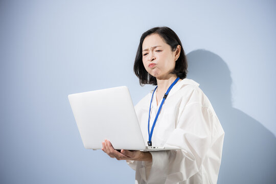 A female office worker looking at her laptop with a troubled expression; a Japanese businesswoman struggling with work-related issues, mistakes, problems, and stress