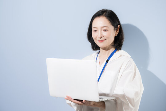ノートパソコンを持って笑顔を見せる女性会社員、デジタルを活用して働く日本人ビジネスウーマン