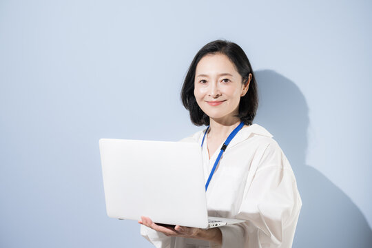 ノートパソコンを持って笑顔を見せる女性会社員、デジタルを活用して働く日本人ビジネスウーマン