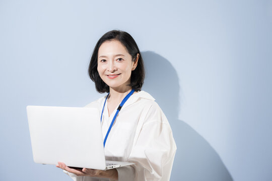 ノートパソコンを持って笑顔を見せる女性会社員、デジタルを活用して働く日本人ビジネスウーマン