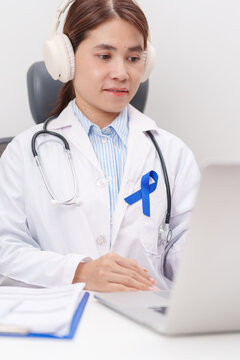 doctor using laptop for telehealth, online consultation and meeting about Navy blue ribbon concept of March Colorectal and Colon Cancer Awareness month, May Arthritis awareness, Juvenile arthritis