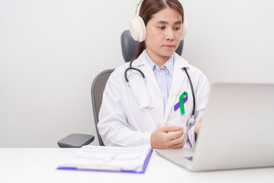 doctor using laptop for telehealth, online consultation and meeting about purple and green ribbon concept of March Anal Cancer Awareness month, Colorectal and Colon Cancer, Healthcare