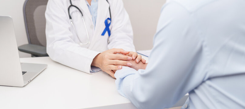 doctor holding patient hand to comfort and support with empathy. Navy blue ribbon concept of March Colorectal and Colon Cancer Awareness month, May Arthritis awareness, July Juvenile arthritis