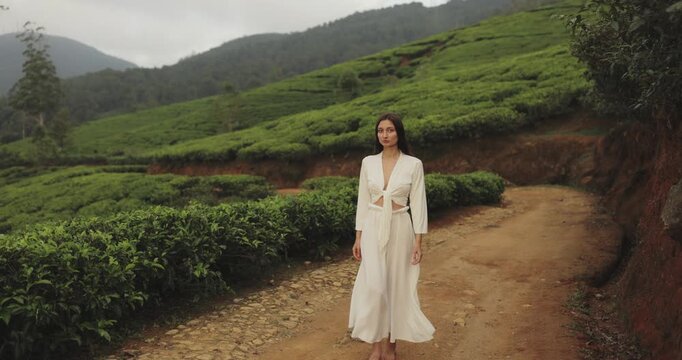 Stylish Woman In White Suit Walking Gracefully Through Green Tea Fields