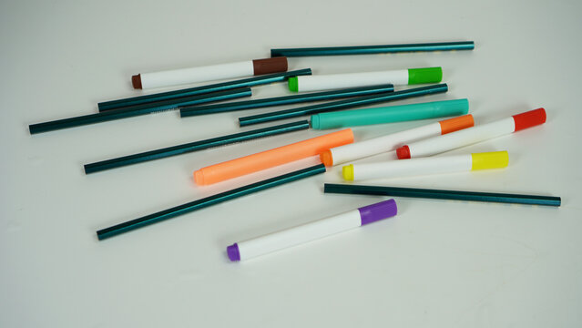Several colorful markers and pencils scattered on a white background, children's education concept, children's school equipment,