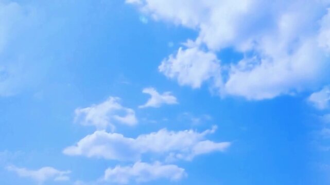 White fluffy clouds moving across the bright blue sky
