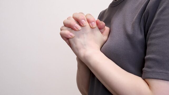 胸の前で両手を組む女性の上半身