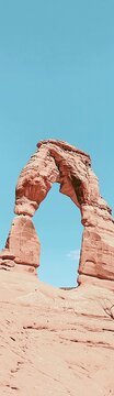 Natural sandstone arch formation against clear blue sky