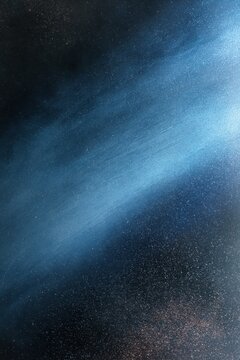 Abstract blue and black textured background with diagonal light streak and glitter particles