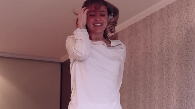 Morning dance. Carefree woman. Smiling happy female with headphones enjoying joyful music bedroom lifestyle at cozy home.