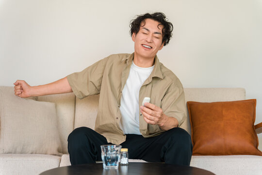 Smiling Man Checking His Temperature with a Thermometer, Relieved After Recovering from a Fever