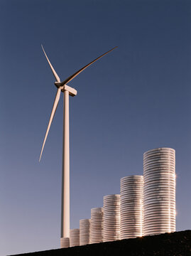 MetadataWind turbine and stacked coins against clear sky symbolize renewable energy investment and sustainable finance