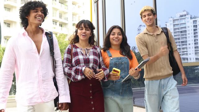 Diverse group of indian gen z college students enjoy conversing outdoors on campus, holding notebooks and wearing backpacks, representing education, friendship, and learning together