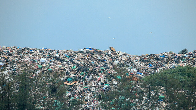 A massive mountain of flood debris and accumulated garbage left behind after a severe disaster, illustrating the scale of post-flood recovery and search operations.