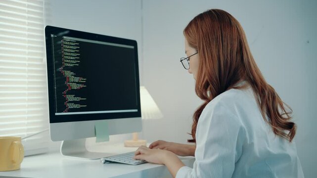 Young female programmer typing on a keyboard, debugging code. IT specialist developing a new website or application in a modern office