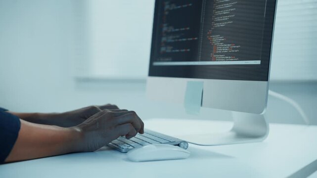 African american developer typing code on computer keyboard while working on a new software project in a modern office