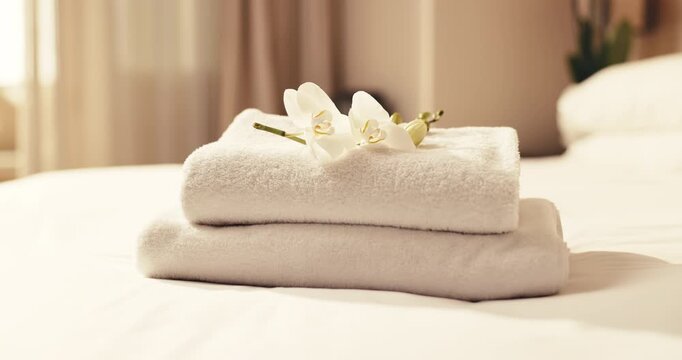 Towel, stack and flowers in bedroom for beauty spa, accommodation or hospitality in luxury resort. Empty, fabric and sheets with floral decor for zen getaway, holiday vacation or weekend in retreat