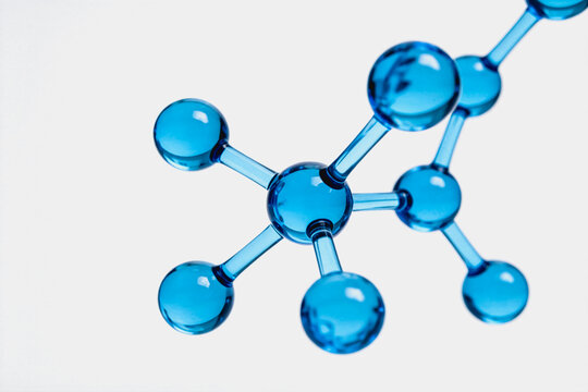 A three-dimensional molecular model made of transparent blue glass, showing atomic bonds and structure, isolated on a white background for scientific use.
