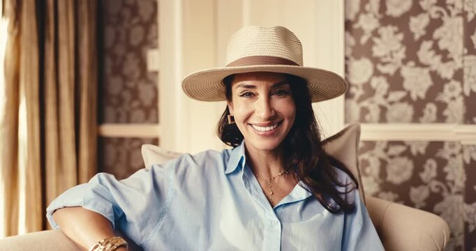 Travel, lounge or happy woman at hotel for relax with peace, luxury holiday or comfort with hat. Face, mature person or smile in upscale resort for hospitality, vacation tourist or premium experience