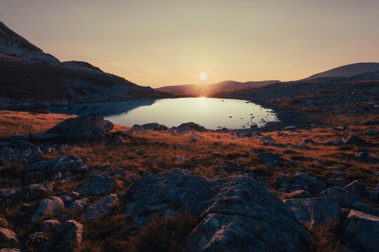  Golden sunrise illuminating a high altitude glacial lake in the Parang mountains, Romania.