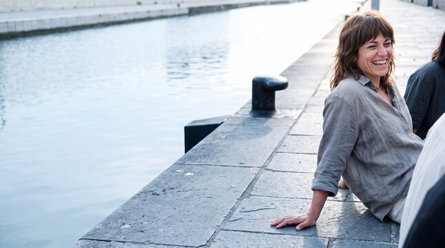 Frau sitzt lachend mit Freunden am Kanal im Sommer
