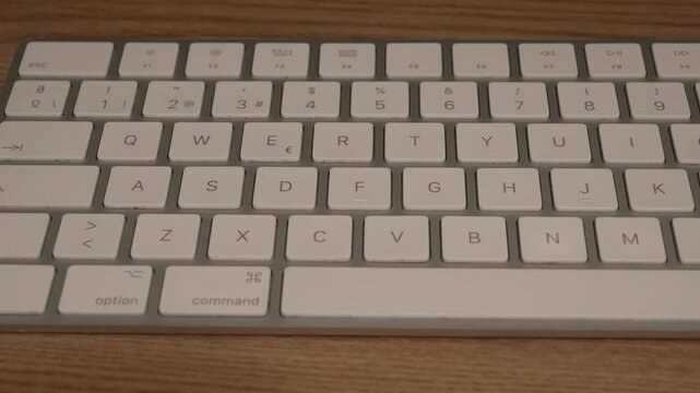 Wireless White Computer Keyboard on Wooden Desk, Static Close-Up