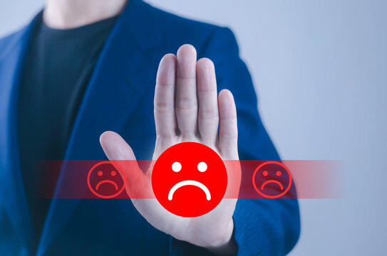 Business professional showing a stop hand gesture with a sad face icon, symbolizing negative feedback, customer dissatisfaction, rejection, poor service, complaints, and brand reputation concerns now.
