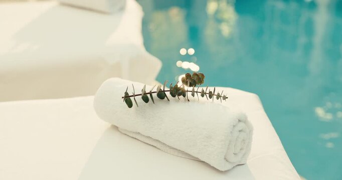 Towel, plant and pool with massage table in luxury resort for zen, accommodation or holiday getaway. Empty, leaves and fabric with cloth by poolside for hospitality, therapy or vacation in beauty spa